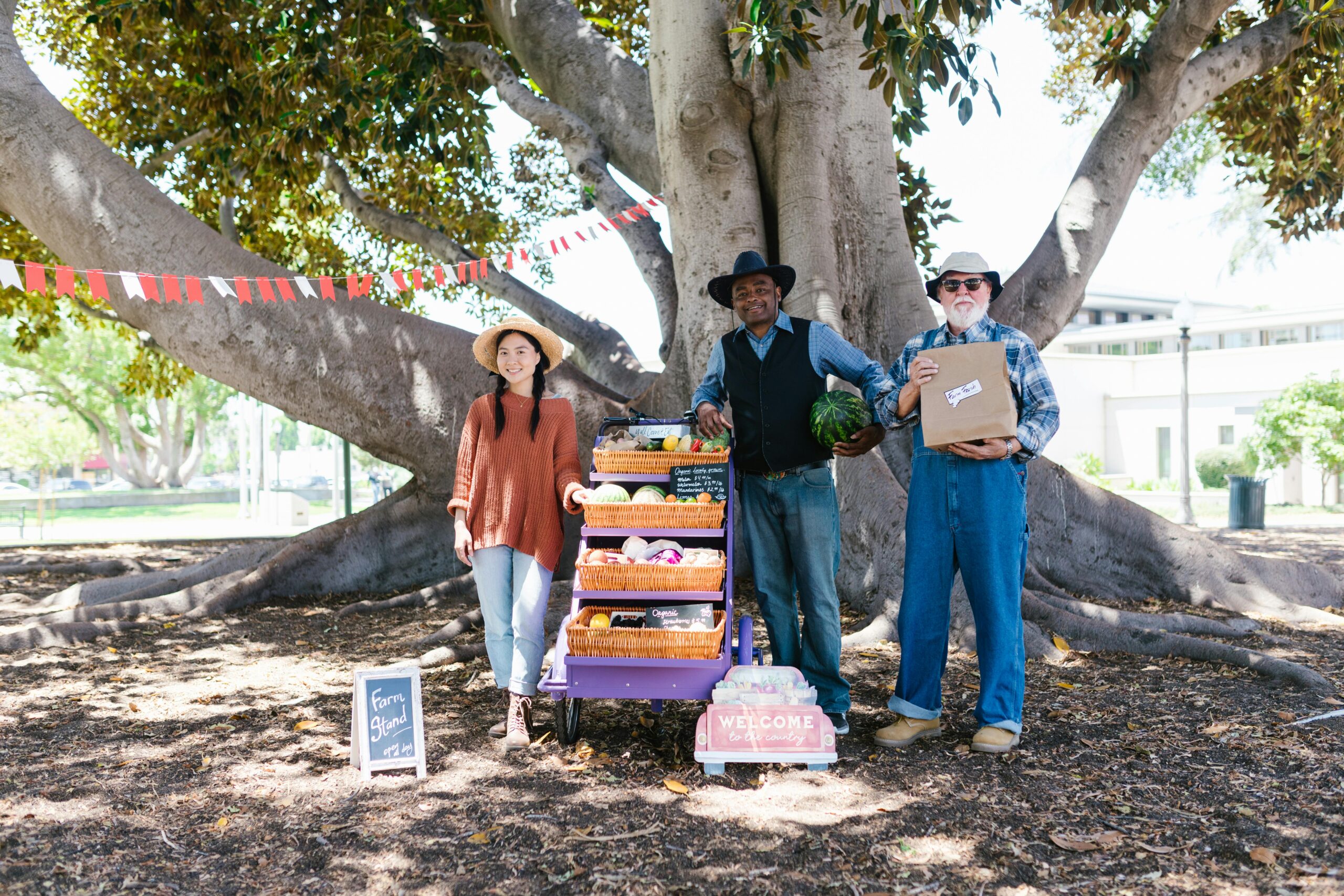 A diverse group of people selling fresh fruits and vegetables at an outdoor farmers market.